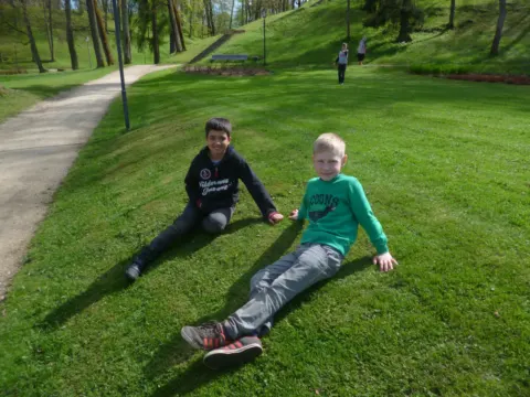 Du mokiniai ilsisi ant žolės parke